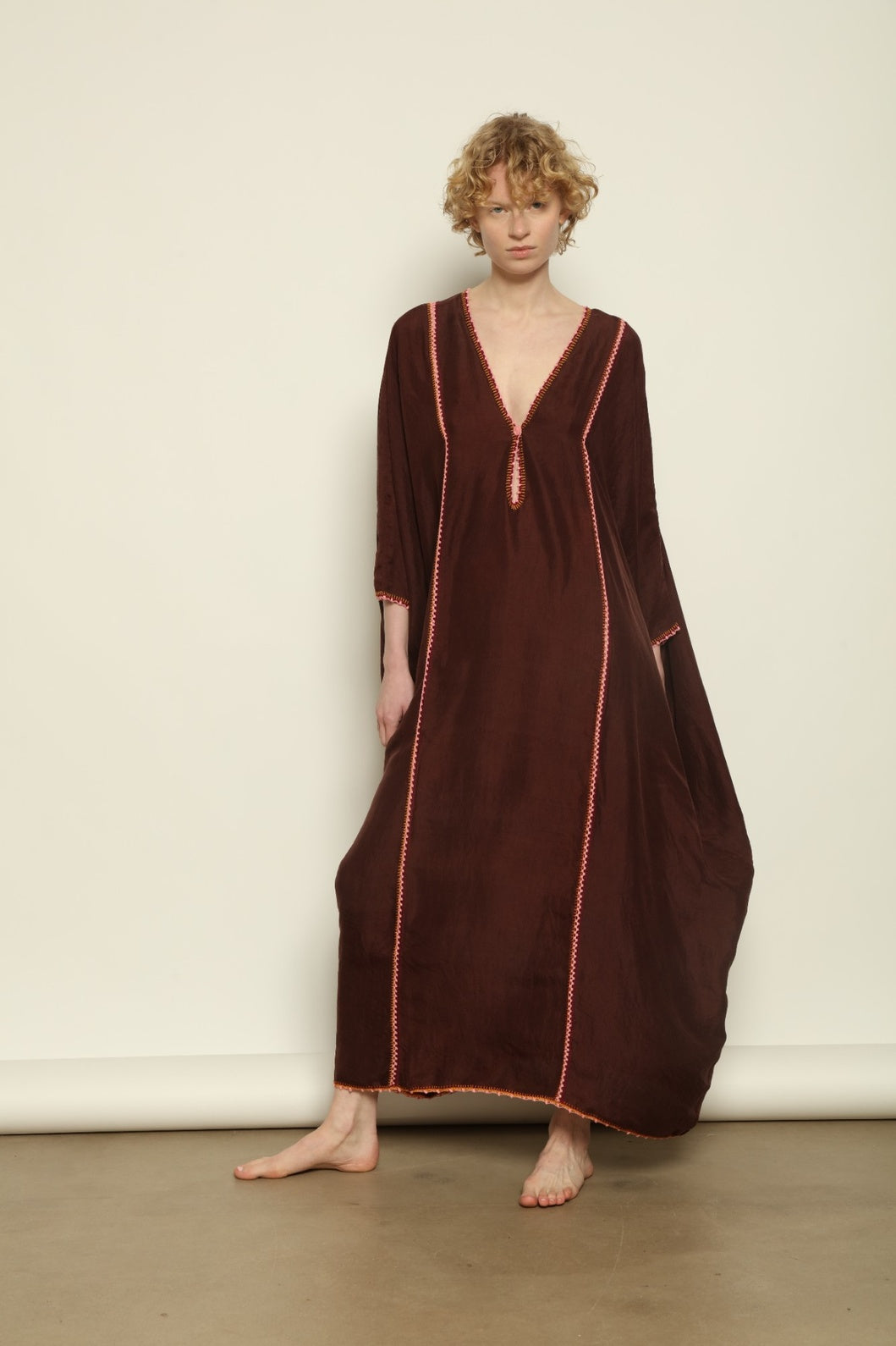 Model is wearing the Thea Brown Silk Dress by Supernaturae x HONS in rich earthy brown handwoven silk from Murshidabad, featuring a soft open back and flowing silhouette. Botanical dyed with natural pigments, this sustainable slow luxury dress shows subtle tonal variations and artisanal craftsmanship, part of the House of Woven Stories selection