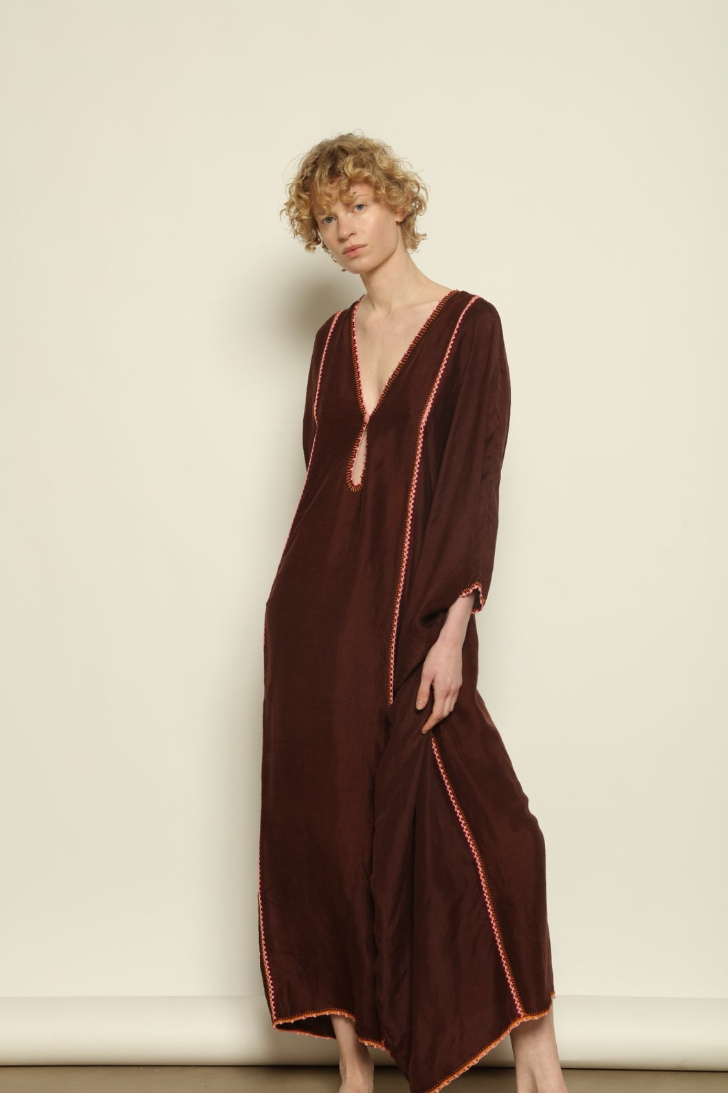 Model is wearing the Thea Brown Silk Dress by Supernaturae x HONS in rich earthy brown handwoven silk from Murshidabad, featuring a soft open back and flowing silhouette. Botanical dyed with natural pigments, this sustainable slow luxury dress shows subtle tonal variations and artisanal craftsmanship, part of the House of Woven Stories selection
