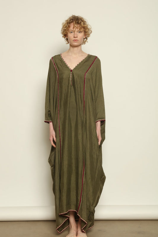 Model is wearing the Thea Olive Silk Dress by Supernaturae in soft olive-toned handwoven silk from Murshidabad, featuring a relaxed flowing silhouette and elegant open back. This sustainable ethical fashion dress is crafted using traditional weaving techniques and natural fibers, designed for everyday wear with a breathable, lightweight drape.