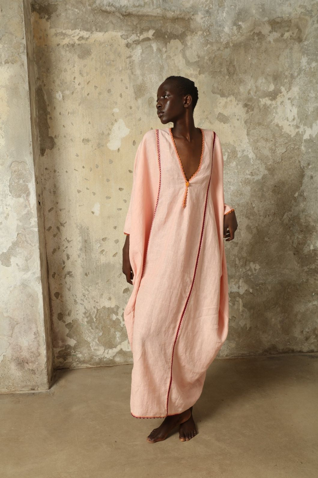 Model is wearing the Thea Pink Linen Dress by Supernaturae x HONS in soft botanical hibiscus pink linen, featuring a relaxed oversized silhouette, open back detail and breathable sustainable fabric. Part of the House of Woven Stories curated selection.
