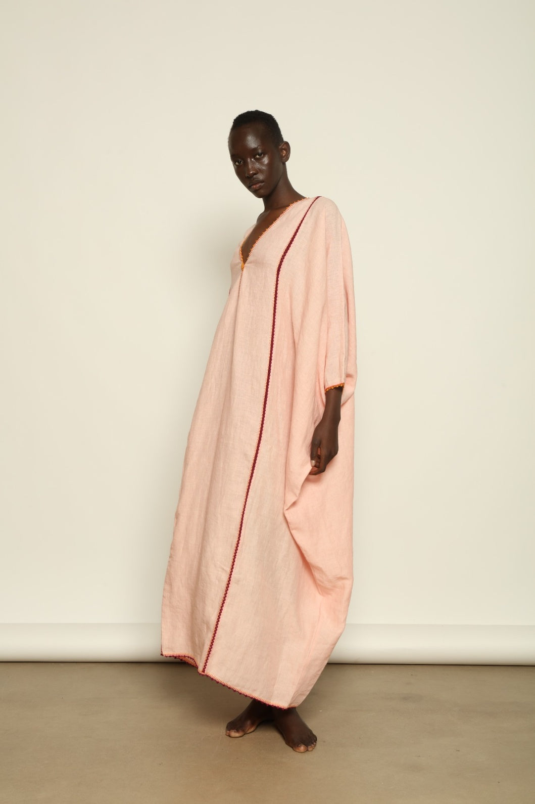Model is wearing the Thea Pink Linen Dress by Supernaturae x HONS in soft botanical hibiscus pink linen, featuring a relaxed oversized silhouette, open back detail and breathable sustainable fabric. Part of the House of Woven Stories curated selection.