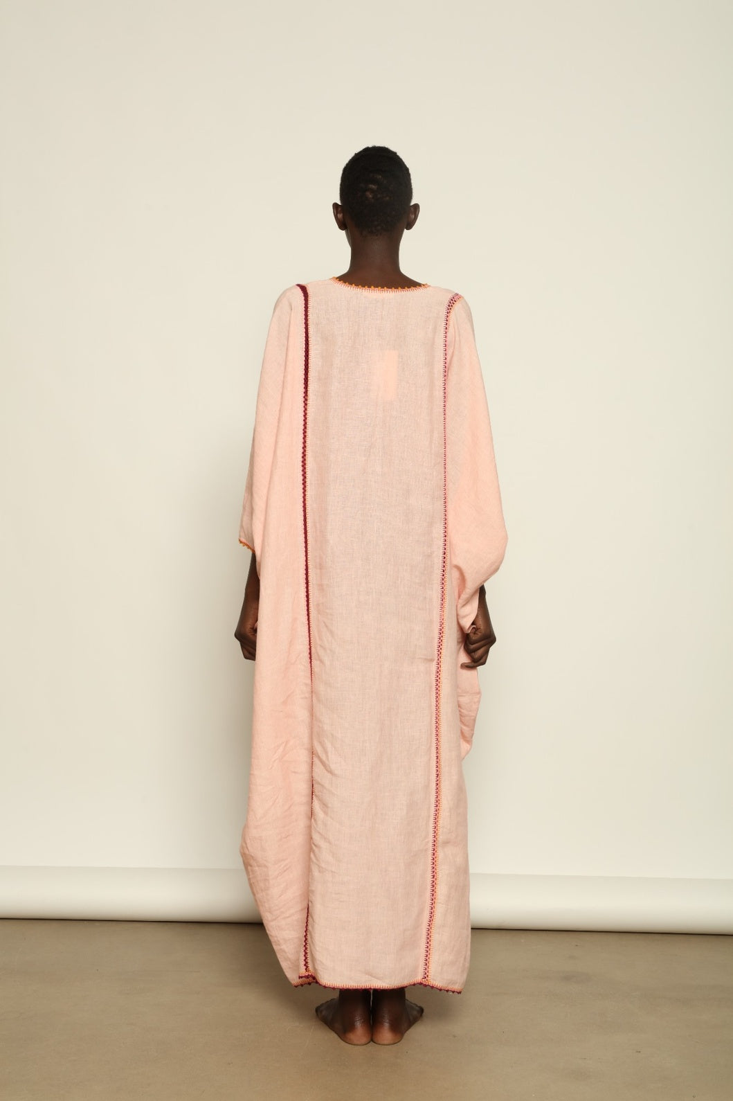 Model is wearing the Thea Pink Linen Dress by Supernaturae x HONS in soft botanical hibiscus pink linen, featuring a relaxed oversized silhouette, open back detail and breathable sustainable fabric. Part of the House of Woven Stories curated selection.