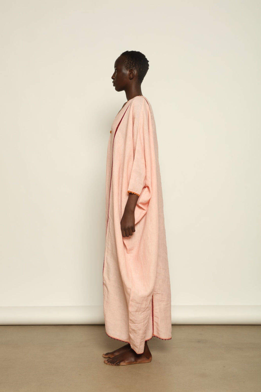 Model is wearing the Thea Pink Linen Dress by Supernaturae x HONS in soft botanical hibiscus pink linen, featuring a relaxed oversized silhouette, open back detail and breathable sustainable fabric. Part of the House of Woven Stories curated selection.