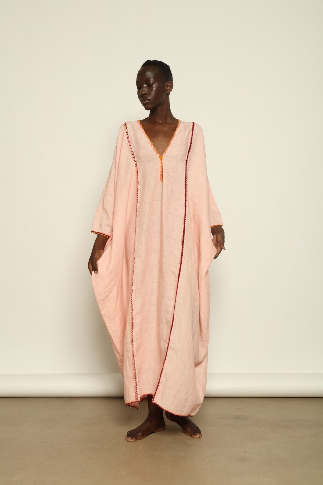 Model is wearing the Thea Pink Linen Dress by Supernaturae x HONS in soft botanical hibiscus pink linen, featuring a relaxed oversized silhouette, open back detail and breathable sustainable fabric. Part of the House of Woven Stories curated selection.