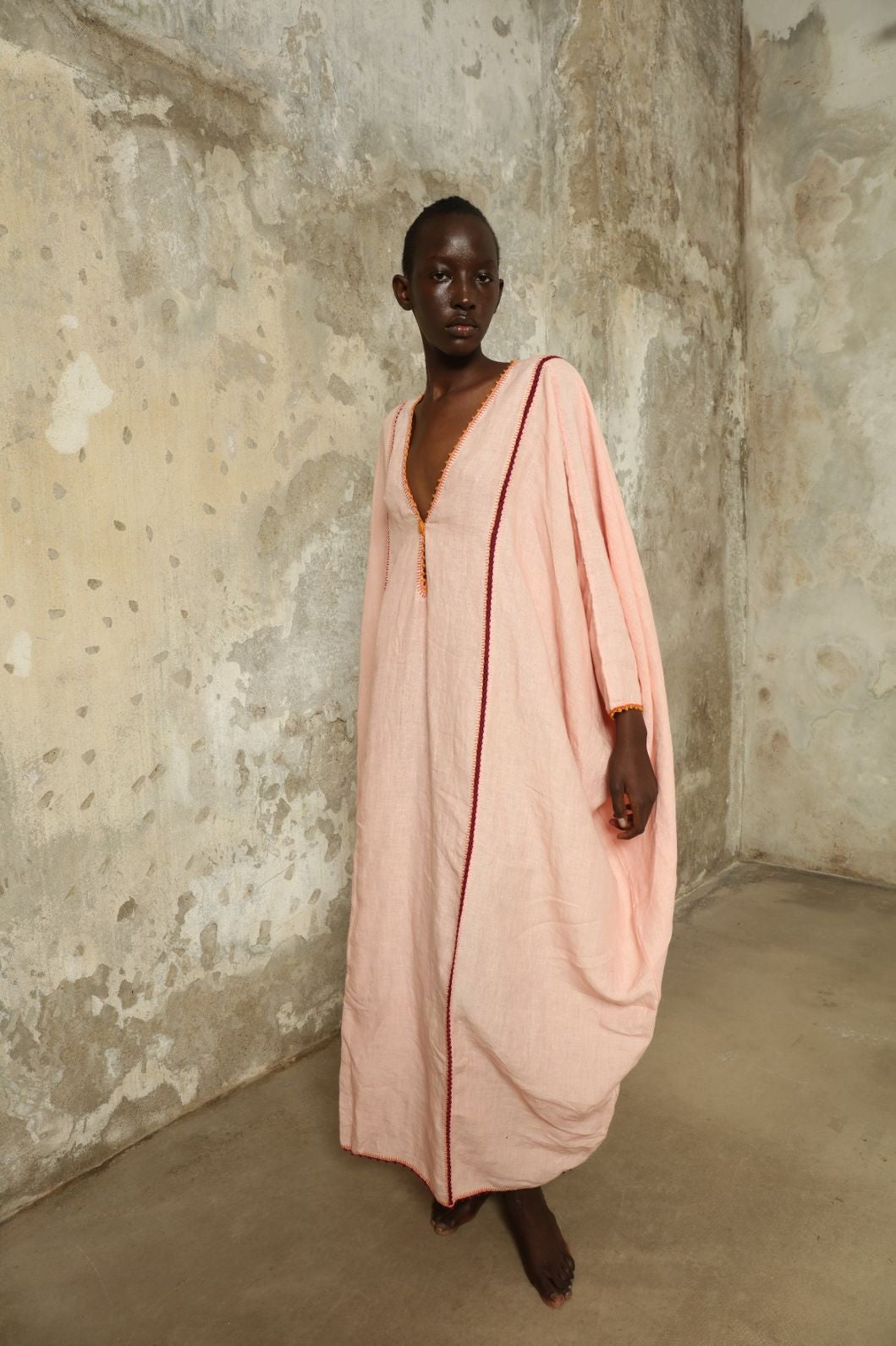 Model is wearing the Thea Pink Linen Dress by Supernaturae x HONS in soft botanical hibiscus pink linen, featuring a relaxed oversized silhouette, open back detail and breathable sustainable fabric. Part of the House of Woven Stories curated selection.