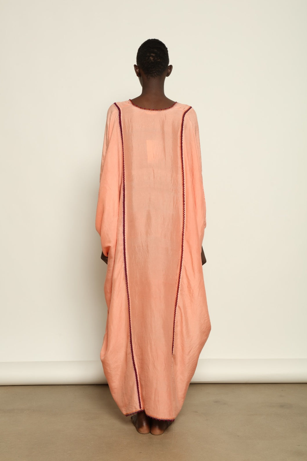 Model is wearing the Thea Rose Silk Dress by Supernaturae x HONS, crafted in handwoven silk from Murshidabad with a soft botanical rose dye finish, featuring a relaxed flowing silhouette and deep open back design. Part of the House of Woven Stories selection, this sustainable slow luxury piece reflects ethical artisan craftsmanship and natural dye variations.