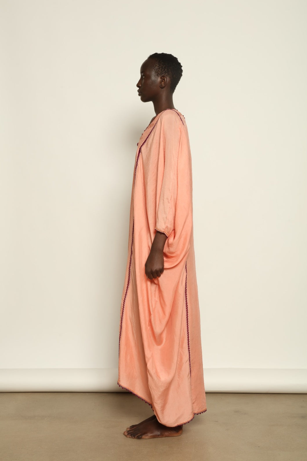 Model is wearing the Thea Rose Silk Dress by Supernaturae x HONS, crafted in handwoven silk from Murshidabad with a soft botanical rose dye finish, featuring a relaxed flowing silhouette and deep open back design. Part of the House of Woven Stories selection, this sustainable slow luxury piece reflects ethical artisan craftsmanship and natural dye variations.