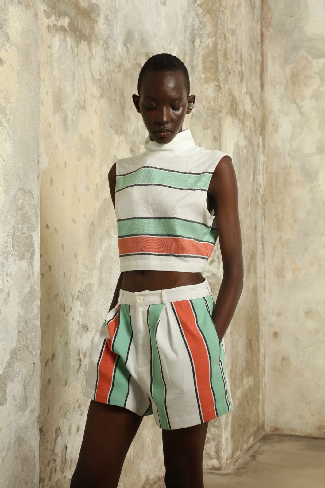 Model is wearing The Cropped Turtleneck by Marrakshi Life, part of House of Nomad Stories collection, handwoven artisanal cotton top with boxy architectural silhouette, high turtleneck, and breathable weave