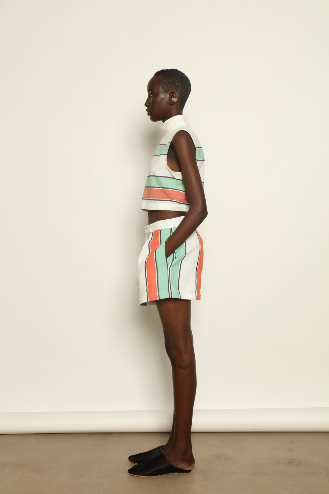 Model is wearing The Cropped Turtleneck by Marrakshi Life, part of House of Nomad Stories collection, handwoven artisanal cotton top with boxy architectural silhouette, high turtleneck, and breathable weave