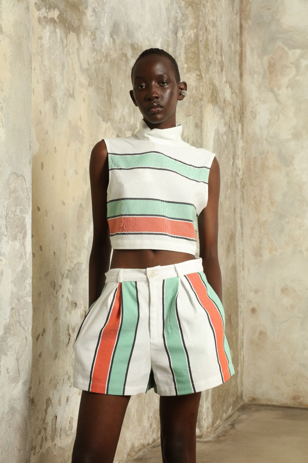 Model is wearing The Cropped Turtleneck by Marrakshi Life, part of House of Nomad Stories collection, handwoven artisanal cotton top with boxy architectural silhouette, high turtleneck, and breathable weave
