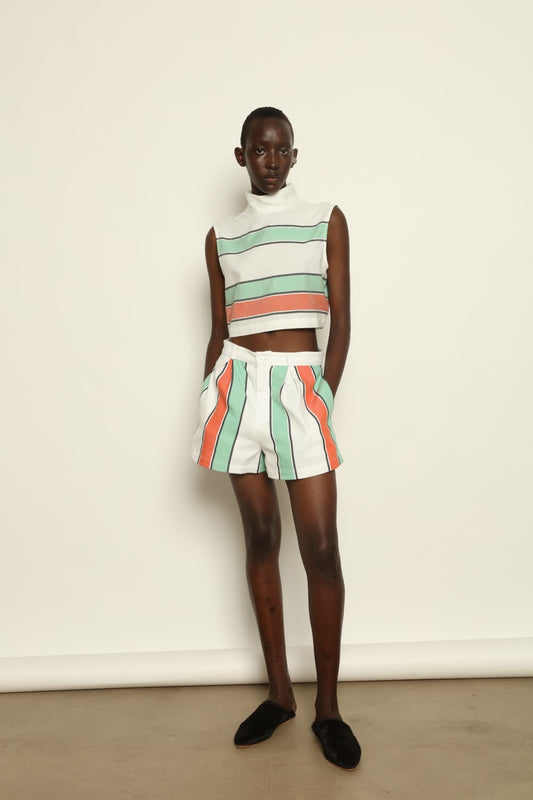 Model is wearing The Cropped Turtleneck by Marrakshi Life, part of House of Nomad Stories collection, handwoven artisanal cotton top with boxy architectural silhouette, high turtleneck, and breathable weave