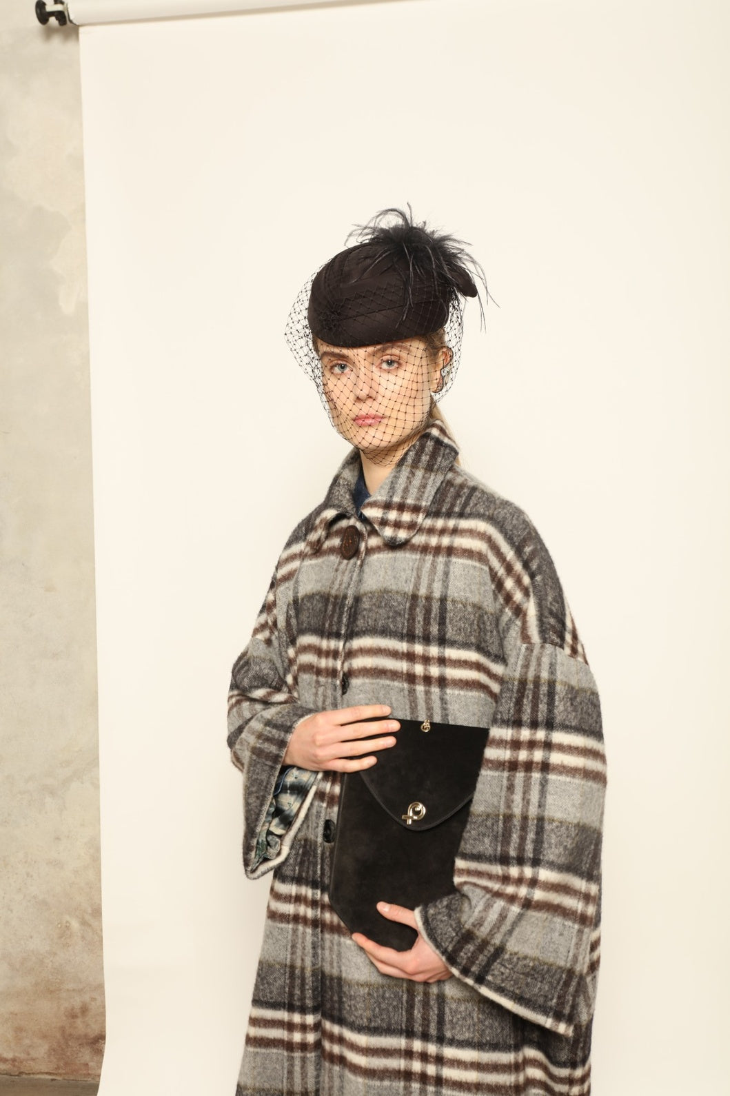 Model is wearing the Tiflis Checked Coat by House of Woven Stories, crafted from a soft wool blend with muted grey and brown checks, featuring an oversized silhouette, wide sleeves, and structured collar for timeless elegance.