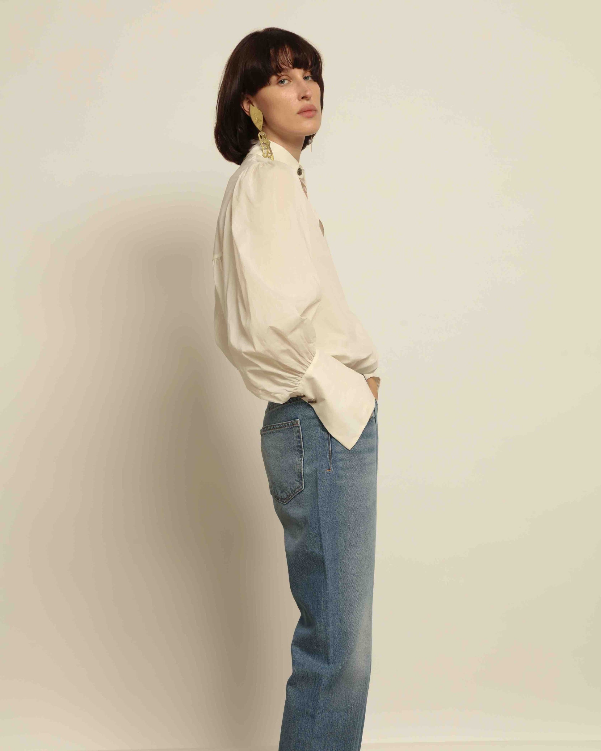 Model is wearing the Tilda Mid-Rise Draped Straight Jean by B Sides in classic indigo denim, mid-rise fit with straight tapered leg and curved inseam for a leg-lengthening silhouette.