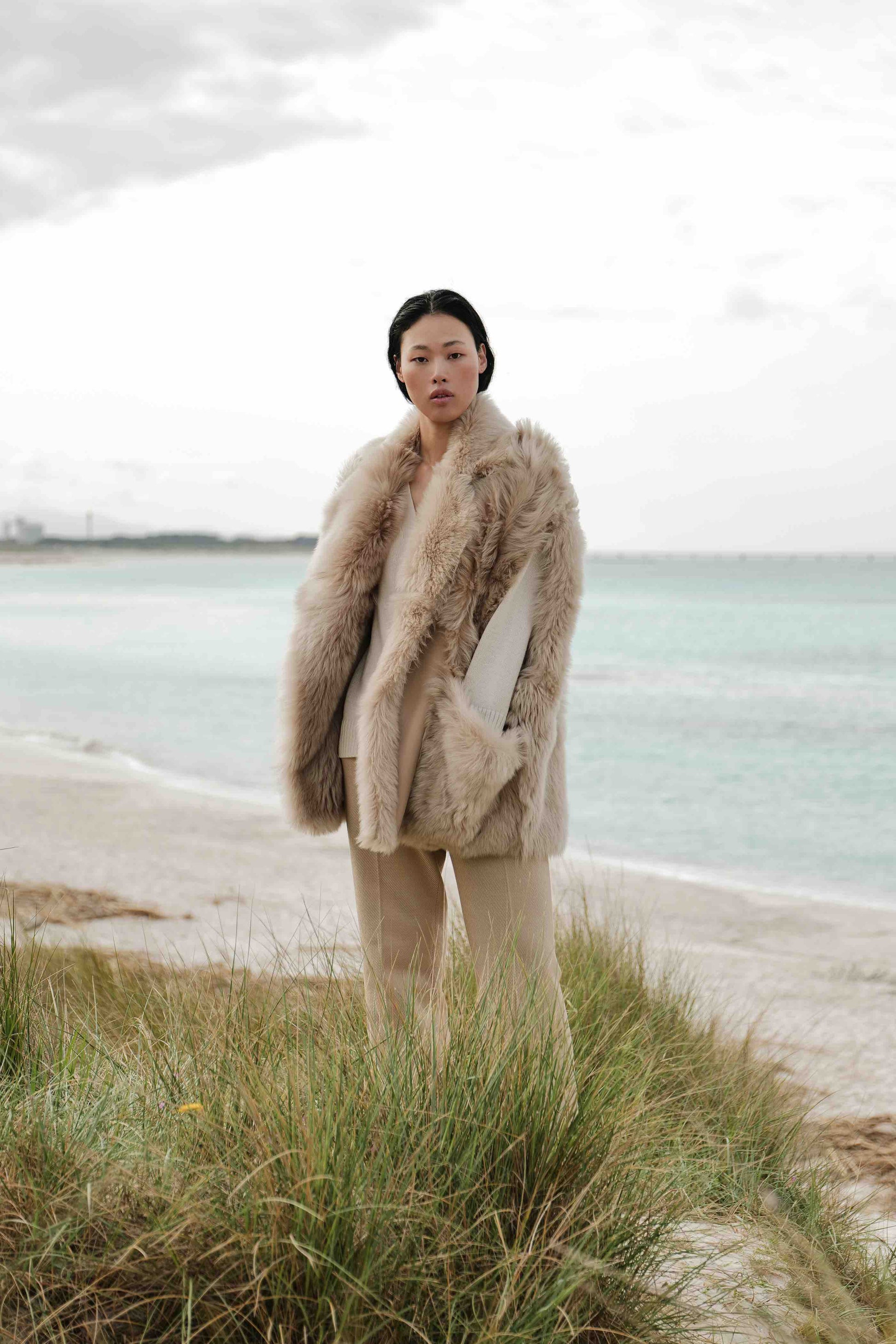 Model is wearing the Toscana Sabbia Shearling Vest by Blancha, made from 100% Toscana sheepskin in a soft Sabbia shade, showcasing warmth, fluid drape, and versatile layering. Part of House of Woven Stories selection.
