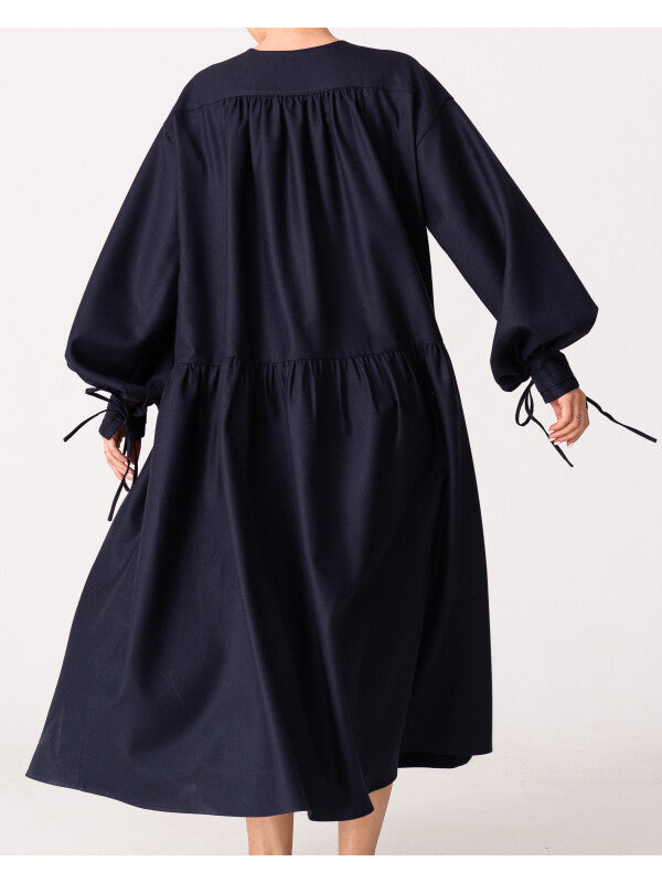 Model is wearing the Winter Calla Dress by Les Vacances d’Irina, a full-length navy merino wool dress with drop-waist silhouette, billowy sleeves, and bow cuffs, handmade in Bucharest and available at House of Woven Stories.