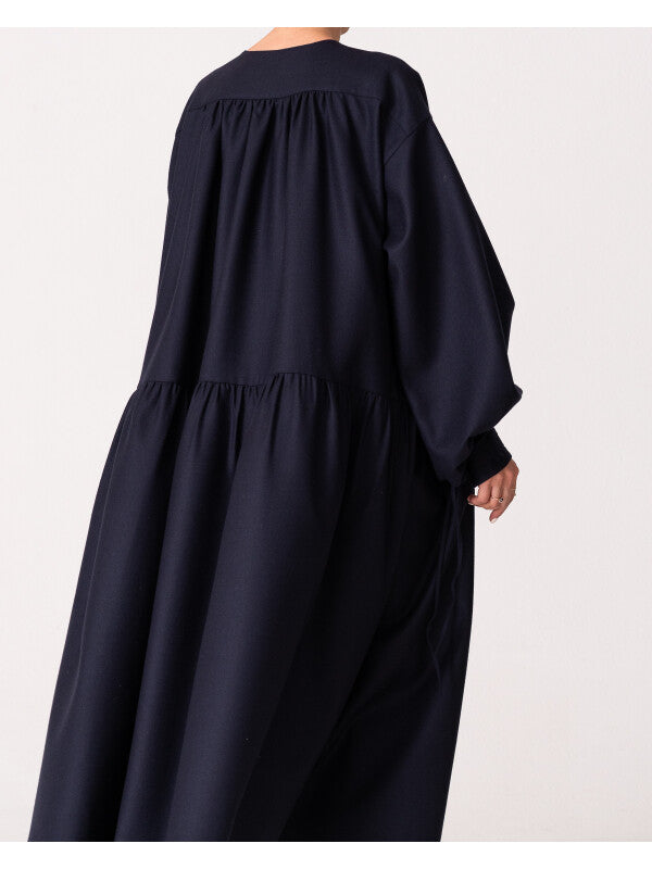 Model is wearing the Winter Calla Dress by Les Vacances d’Irina, a full-length navy merino wool dress with drop-waist silhouette, billowy sleeves, and bow cuffs, handmade in Bucharest and available at House of Woven Stories.