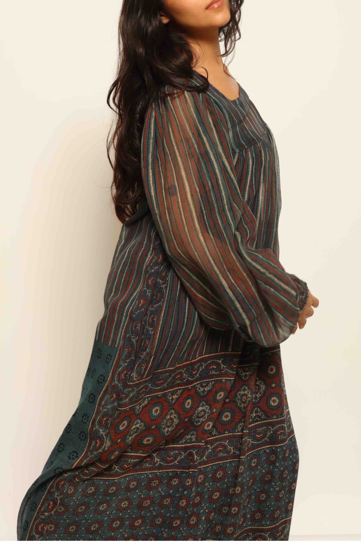 Model is wearing the Woodstock Dark silk dress by House Of Woven Stories, handcrafted in Italy from re-wearable sari fabric, featuring sheer sleeves, handprinted details, and a flowing silhouette.
