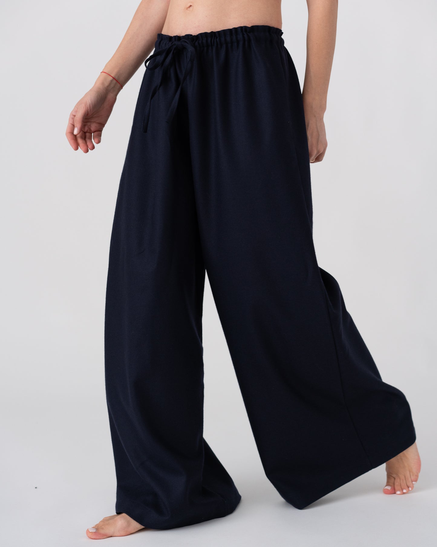 Model is wearing the Wool Black Pantalons by Les Vacances d’Irina, wide-leg handmade jersey-knit wool pants with adjustable drawstring waist and side pockets, available at House of Woven Stories.