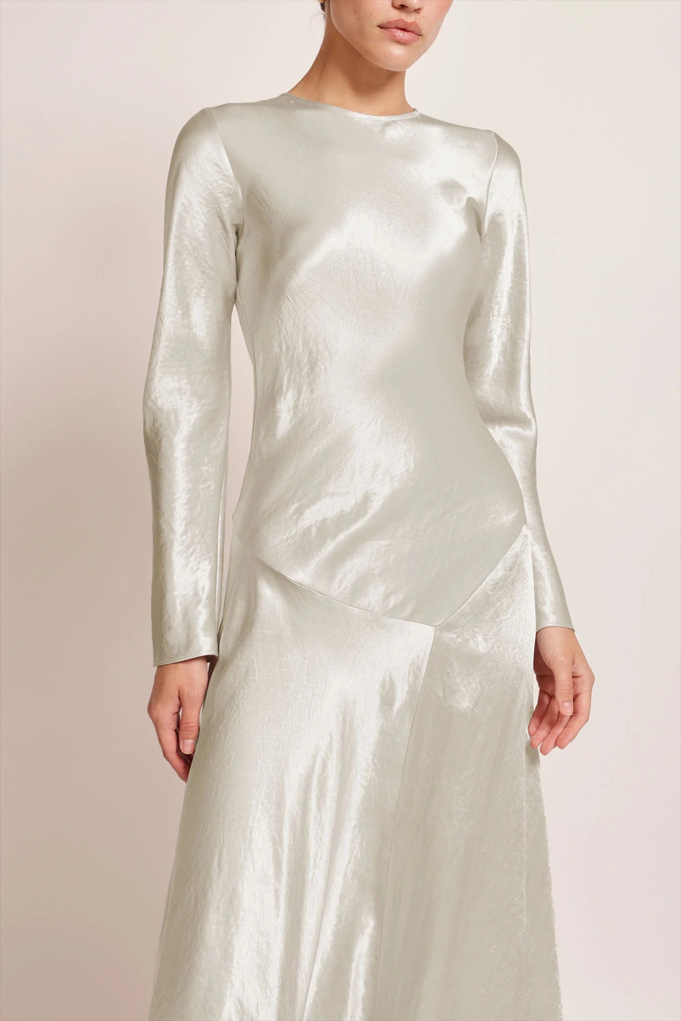 Model wearing a silver silk satin Yara Dress by Abadia from the House of Nomad Stories collection, featuring a bias-cut silhouette, long sleeves, and a fluid elegant drape with a subtle metallic sheen.